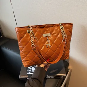 Quilted brown tote bag with gold chain strap and deer charm in a modern urban style