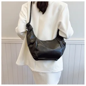 Detail of black crescent shoulder bag with pleated leather and decorative knot strap