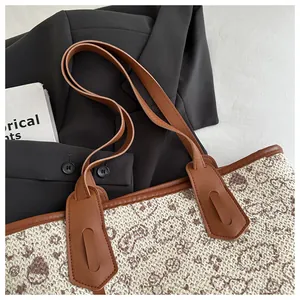 Macro view of woven tote bag texture with brown floral patterns and leather straps