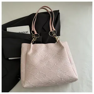 Detail of pink pleated tote bag featuring white floral embroidery and gold chain strap