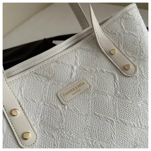 Detailed close-up of white striped fabric tote with floral embroidery and leather brand tag