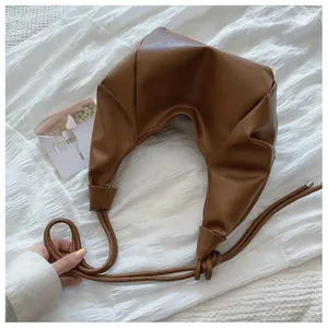 Detail of crescent pleated leather bag with a knotted strap and metallic buckle