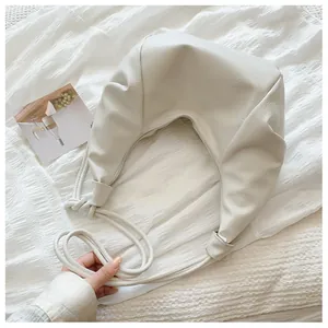 Close-up of ivory pleated hobo bag featuring litchi grain texture and knotted shoulder strap