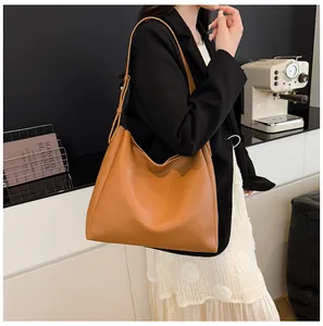 Side view of a large brown leather tote bag with adjustable straps on a female model