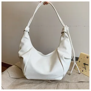 Detail view of cream white pleated dumpling bag with elegant knotted shoulder strap design