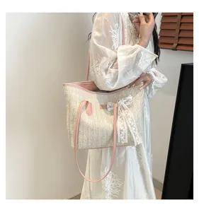 Détail du sac cabas en paille tissée avec bride en cuir rose et nœud en dentelle