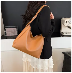 Model view of large camel leather tote bag with wide strap in a minimalist setting