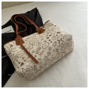 Detail of woven tote bag featuring vintage paisley patterns and brown faux leather straps