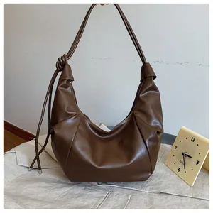 Detail of soft brown leather dumpling bag with knotted strap and metal zipper