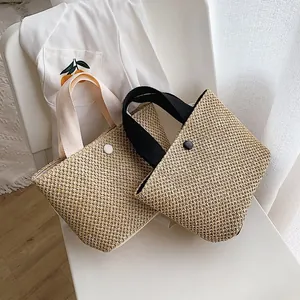 Woven straw handbag in black and beige for summer beach vacations with fabric handles