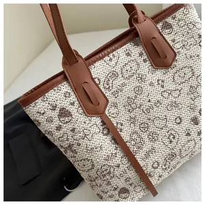 Detail of woven tote bag showing beige texture with brown pattern and leather handle