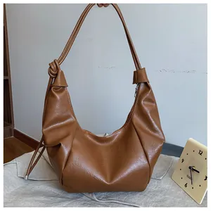 Detail of caramel leather hobo bag featuring drawstring straps and pleated texture finish