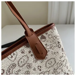 Close-up of woven jacquard tote bag with dark brown leather handle and fine stitching