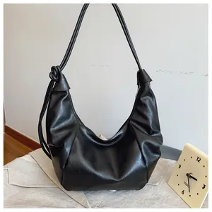 Detail of black crescent hobo bag with knotted shoulder strap and soft faux leather texture