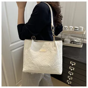 Close-up of white tote bag with textured pleated fabric and gold metal ring hardware