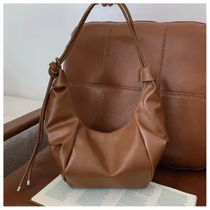 Detail of a brown textured faux leather hobo bag with a decorative knotted shoulder strap