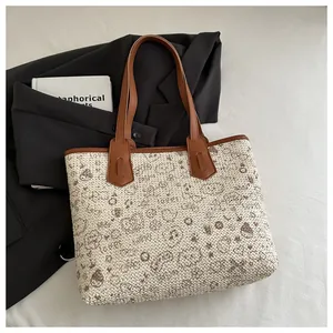 Macro shot of large tote bag with woven cream texture, brown leather handles and art patterns