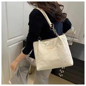 Detail of white tote bag with floral jacquard texture and metal chain strap on shoulder