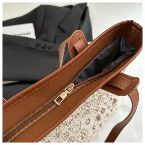 Close-up of the metal zipper closure and spacious interior of the brown woven tote bag