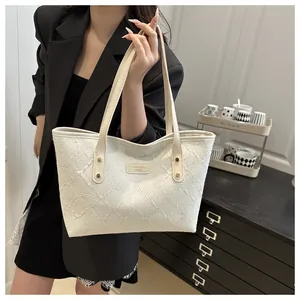 Detail of white textured tote bag with cream leather handles and metal rivet reinforcement