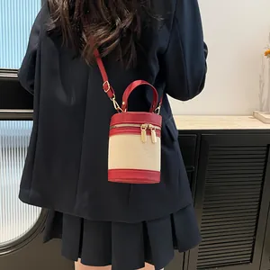 Detail of color-block bucket bag featuring beige canvas, red leather and gold zipper
