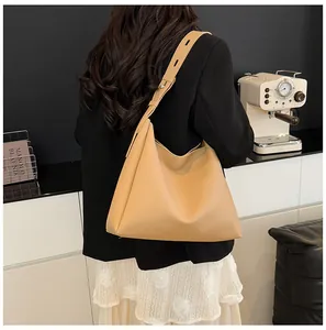 Detail of light brown matte leather tote bag with adjustable wide shoulder strap on model