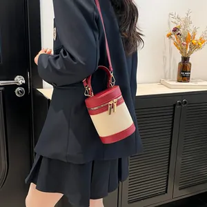 Detail of color-block bucket bag featuring reddish-brown leather trim and ivory woven body