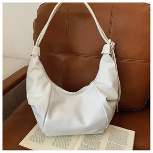 Detail of white pleated hobo bag with leather texture on a brown vintage chair