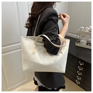 Detail of white jacquard tote bag with textured embroidery and long leather shoulder strap