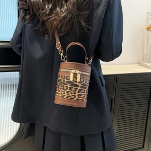 Detail of a leopard print bucket bag with leather stitching and gold metal zippers