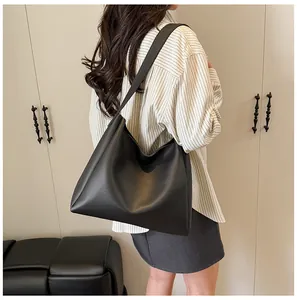 Chic black matte faux leather tote bag shown on shoulder in a minimalist room