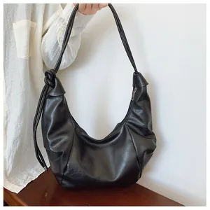 Detail of black matte PU hobo bag with unique knot decoration and silver zipper