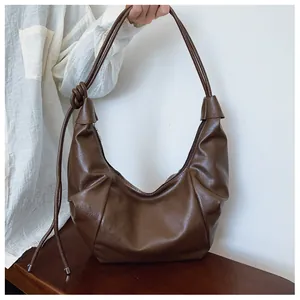 Close-up of dark brown vintage dumpling bag with knotted strap and smooth zipper detail