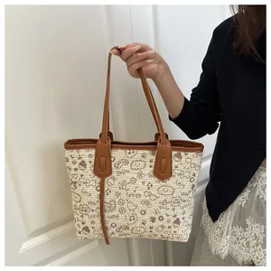 Detail view of woven tote bag with brown leather trim and printed cat motif patterns