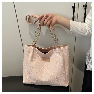 Detail of light pink tote bag with floral embossing and elegant gold chain handles