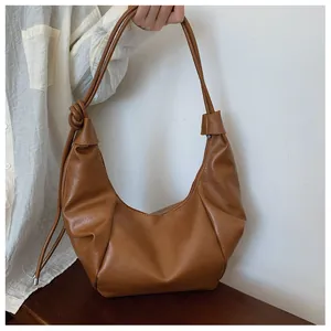Close-up of brown faux leather hobo bag featuring a unique knotted shoulder strap detail