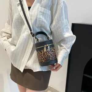 Detail of leopard print bucket bag featuring gold zippers and detachable leather strap