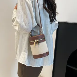 Detail of color-block bucket bag showing canvas and leather patchwork with dual metal zippers