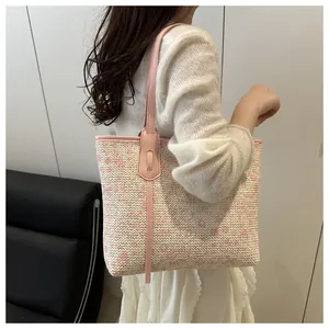 Detail of floral woven tote bag with pink leather straps worn on the shoulder