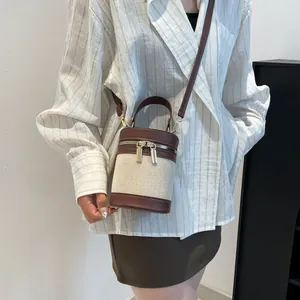 Detail of contrast stitch bucket bag showing canvas texture and brown leather trim