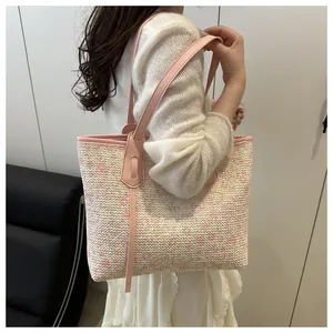 Side view of pink woven tote bag with leather handles shown on shoulder by a model