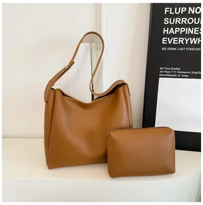 Detail view of brown leather tote bag set including matching zipper pouch on white stand