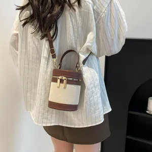 Detailed view of bicolor bucket bag with canvas texture and premium leather trim on model