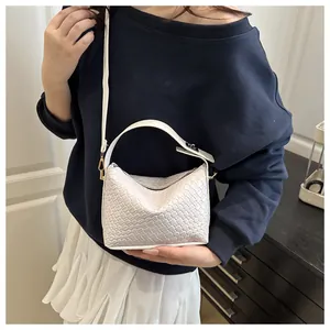 Gros plan d'un sac à bandoulière tissé blanc avec des finitions dorées chic