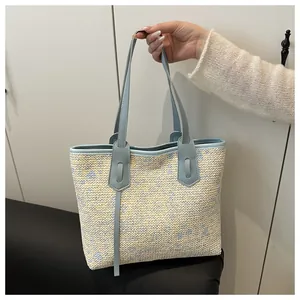 Detailed view of hand-woven straw tote bag with blue leather straps and floral texture