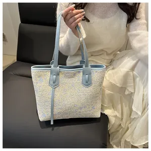 Close-up of woven straw tote bag with light blue faux leather handles and texture detail