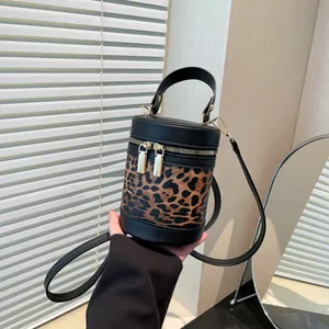 Detailed view of mini leopard print bucket bag with black leather trim and dual gold zippers