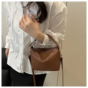 Détail de la texture en cuir tressé marron et de la fermeture éclair argentée du sac à main