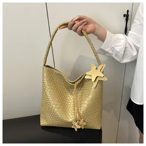 Gros plan du sac fourre-tout doré avec texture tressée et breloques en forme d'étoile