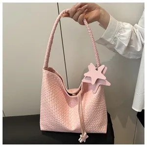 Détail du cabas rose à texture tissée avec breloque étoile et élégants accents de glands